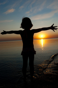 日落海滩上，小女孩开心儿童剪影