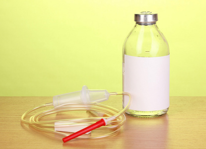 瓶静脉注射抗生素和设置在绿色背景上的木桌上的塑料输液
