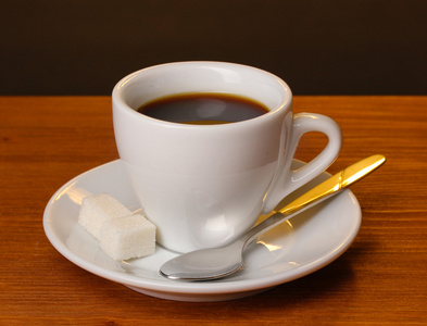 棕色背景上的木桌上的咖啡杯子
