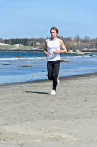 运动年轻男性在海滩上运行