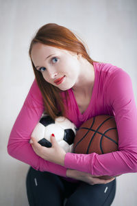 美丽的金发女孩举行足球和篮球球