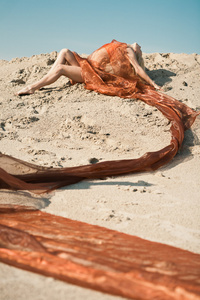 女孩躺在沙子上橙色布