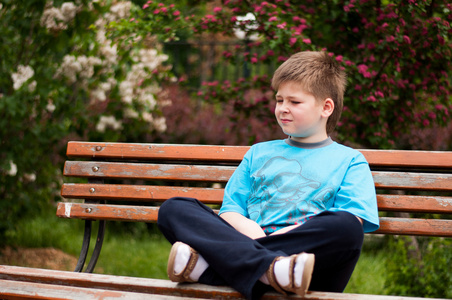 伤心的男孩坐在一张长凳上
