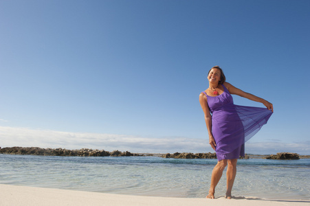 紫色的裙子很高兴在海滩上的女人