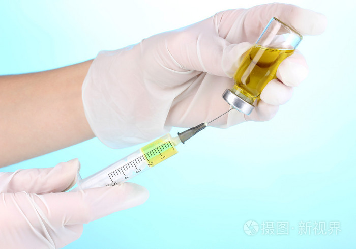 注射器和医疗安瓿在蓝色背景上的手中