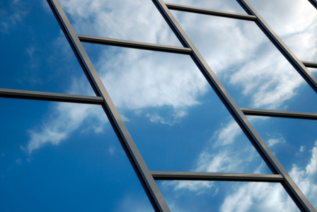从蓝色玻璃现代建筑物的外立面反映了天空