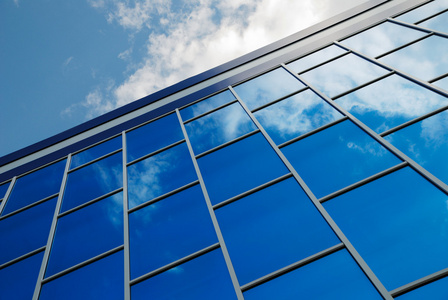 从蓝色玻璃现代建筑物的外立面反映了天空