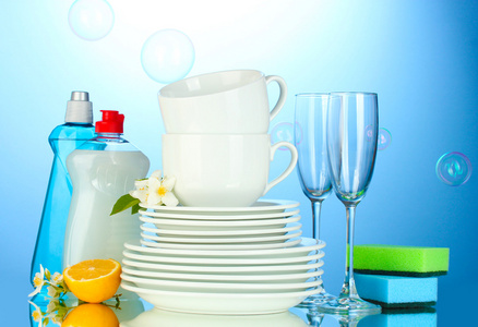 空清洁板材 眼镜 洗洁精 海绵和柠檬在蓝色背景上的杯子