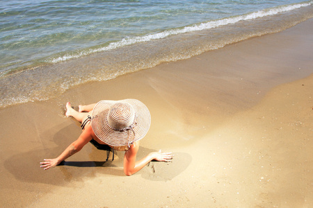 一个戴着帽子的热带海滩上的女孩