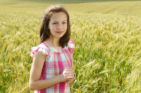 年轻漂亮的女孩在小麦的字段