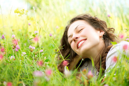 美丽的年轻女子躺在草地上的鲜花。享受自然