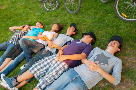 十几岁的男孩和女孩躺在草地上后骑自行车