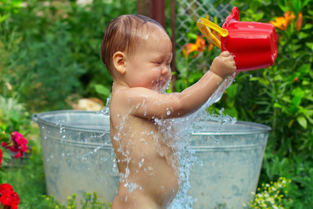 可爱的小宝贝男孩夏天花园里考虑水程序