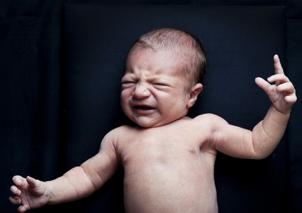 在黑色背景上哭泣的可爱初生女婴的肖像
