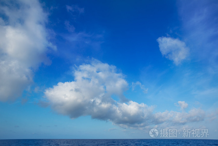 积云在水的地平线上的蓝色天空