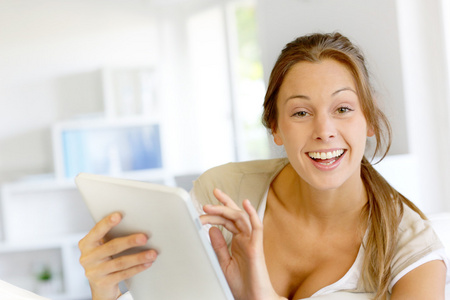 美丽微笑的女人在家中使用数字平板电脑