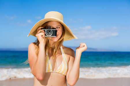 美丽的女人在用相机海滩