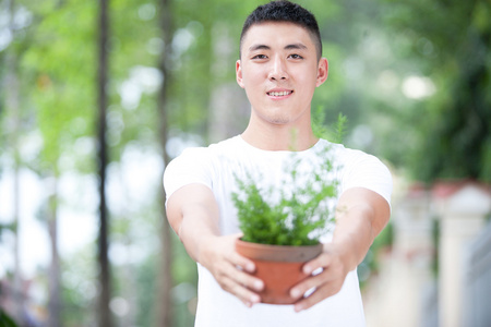 年轻英俊的亚洲学生送一种植物