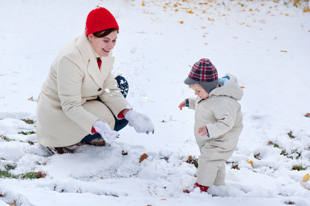 母亲和冬季天蹒跚学步的小男孩