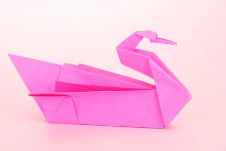 粉红色的背景上的折纸天鹅