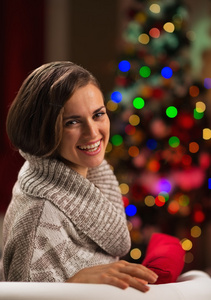 快乐的年轻女人坐在圣诞树前