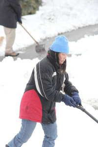 正在车道上铲雪的女士