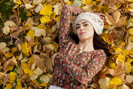 年轻女子躺在秋天的树叶