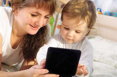 母亲和婴儿的儿子玩数字平板电脑