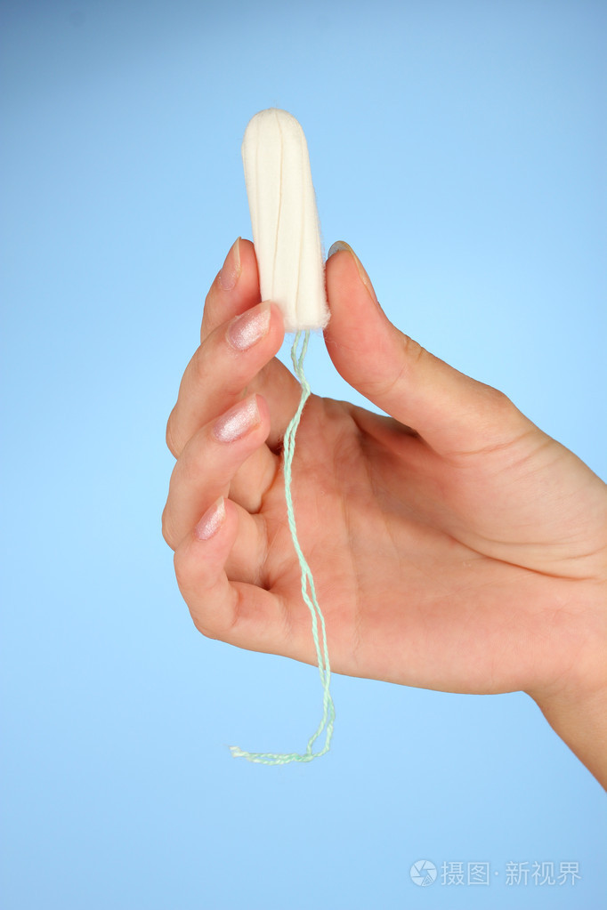 女人的手清洁棉卫生棉条坚持蓝色背景特写