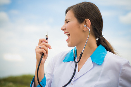 在艾菲尔铁塔的蓝蓝的天空背景上听诊器唱歌的年轻女医生