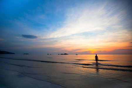 美丽的夕阳海海滩上，在背景中游泳女孩剪影