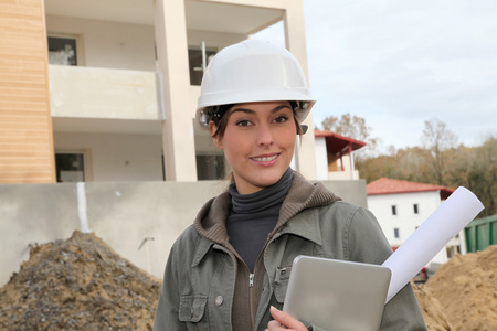 与白色安全头盔站在建筑工地上的女工程师