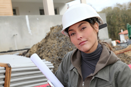 与白色安全头盔站在建筑工地上的女工程师