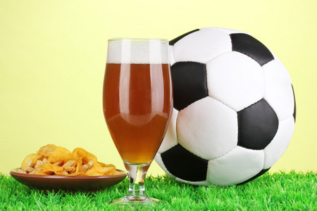 杯啤酒与足球在草地上绿色的背景上