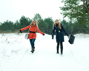 快乐两个漂亮的女孩走在松林在冬天的日子
