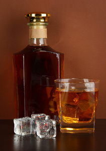 瓶酒和威士忌和棕色背景上的冰玻璃
