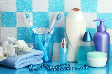 在蓝色瓷砖墙背景上的浴室的架子上浴室配件
