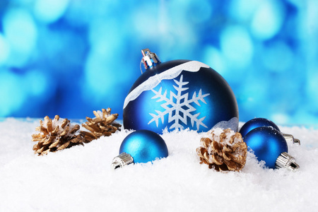 美丽的蓝色圣诞球和锥体在蓝色背景上的雪