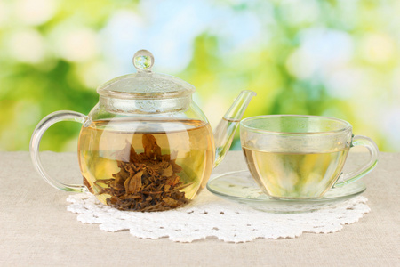 异国情调绿茶与鲜花在明亮的背景上的玻璃茶壶