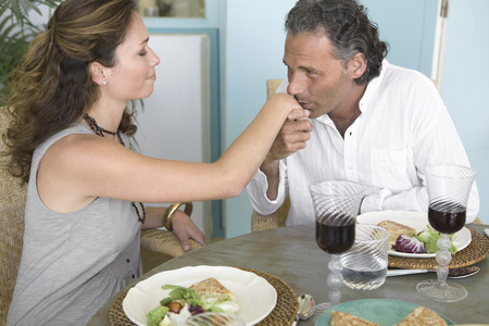 成熟的男人亲吻女人的手时在家吃健康的午餐