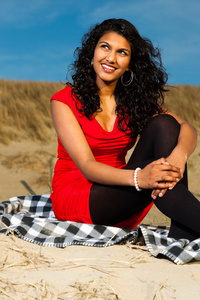 长头发的印度女孩穿红色衣服在海滩上夏天