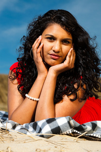 长头发的印度女孩穿红色衣服在海滩上夏天