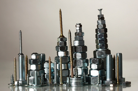 许多类型的金属螺栓 螺钉和螺母上灰色背景