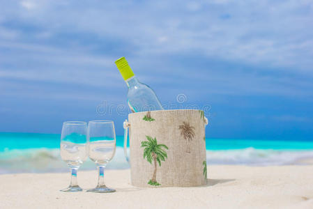 一瓶白葡萄酒和两个玻璃杯在异国情调的沙滩上