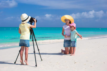 可爱的小女孩在热带海滩为家人拍照