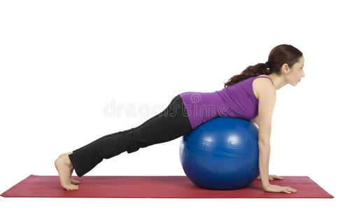年轻的健身妇女在普拉提球上做平衡练习