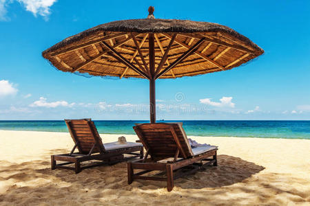白色沙滩上的木制椅子和雨伞