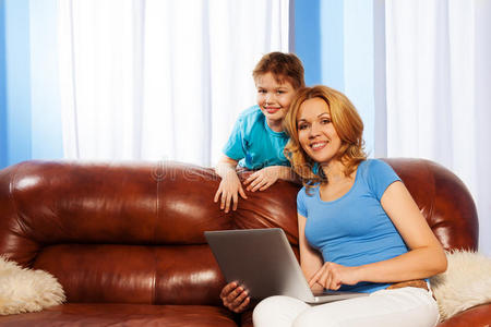 微笑着的妈妈拿着笔记本电脑和儿子在一起