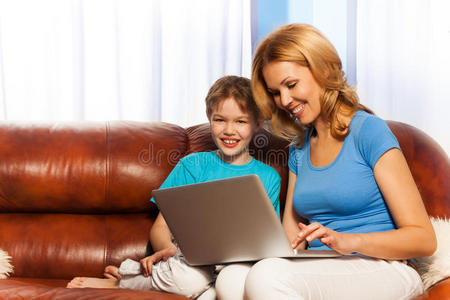 快乐的妈妈和儿子在沙发上放着笔记本电脑