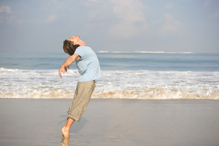 年轻有魅力的男人跳舞在沙滩上，虽然上提示脚趾向后弯曲